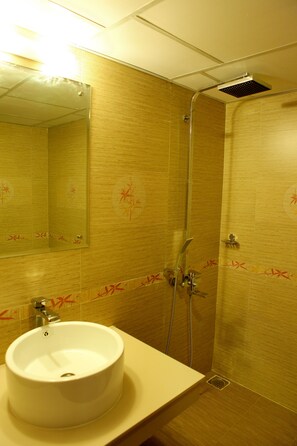 Une salle de bain avec un lavabo, un miroir, une douche et des murs carrelés.