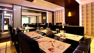 A modern restaurant with multiple dining tables and booths, each with menus and water glasses.