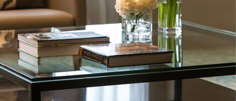 A glass-top coffee table with books and vases of flowers.