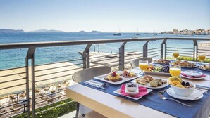 Una mesa de comedor con alimentos para el desayuno y vista al mar.