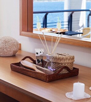 A wooden bedside table with a woven basket, a wooden brush, a candle, and a bottle of Magnolias.