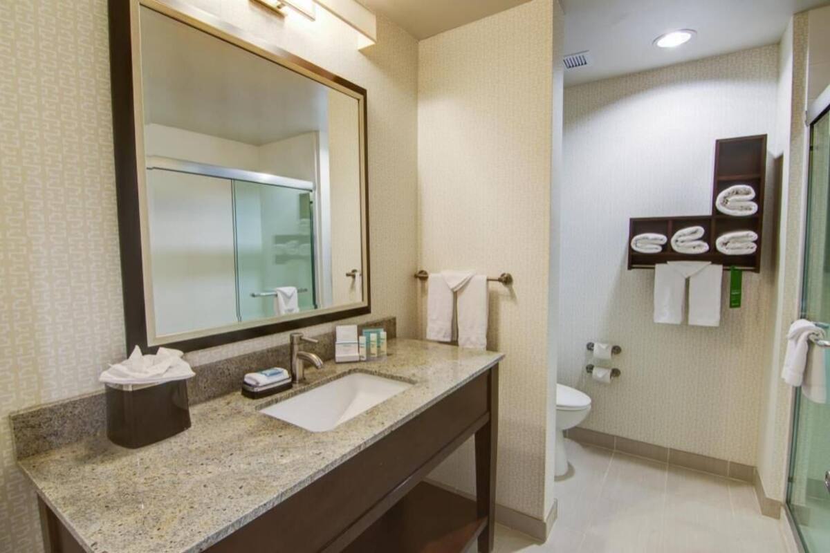 A bathroom with a sink, mirror, towel rack, and glass shower enclosure.