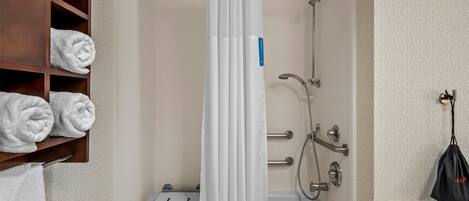 A bathroom with a shower, a towel rack with neatly folded towels, and a handheld showerhead.