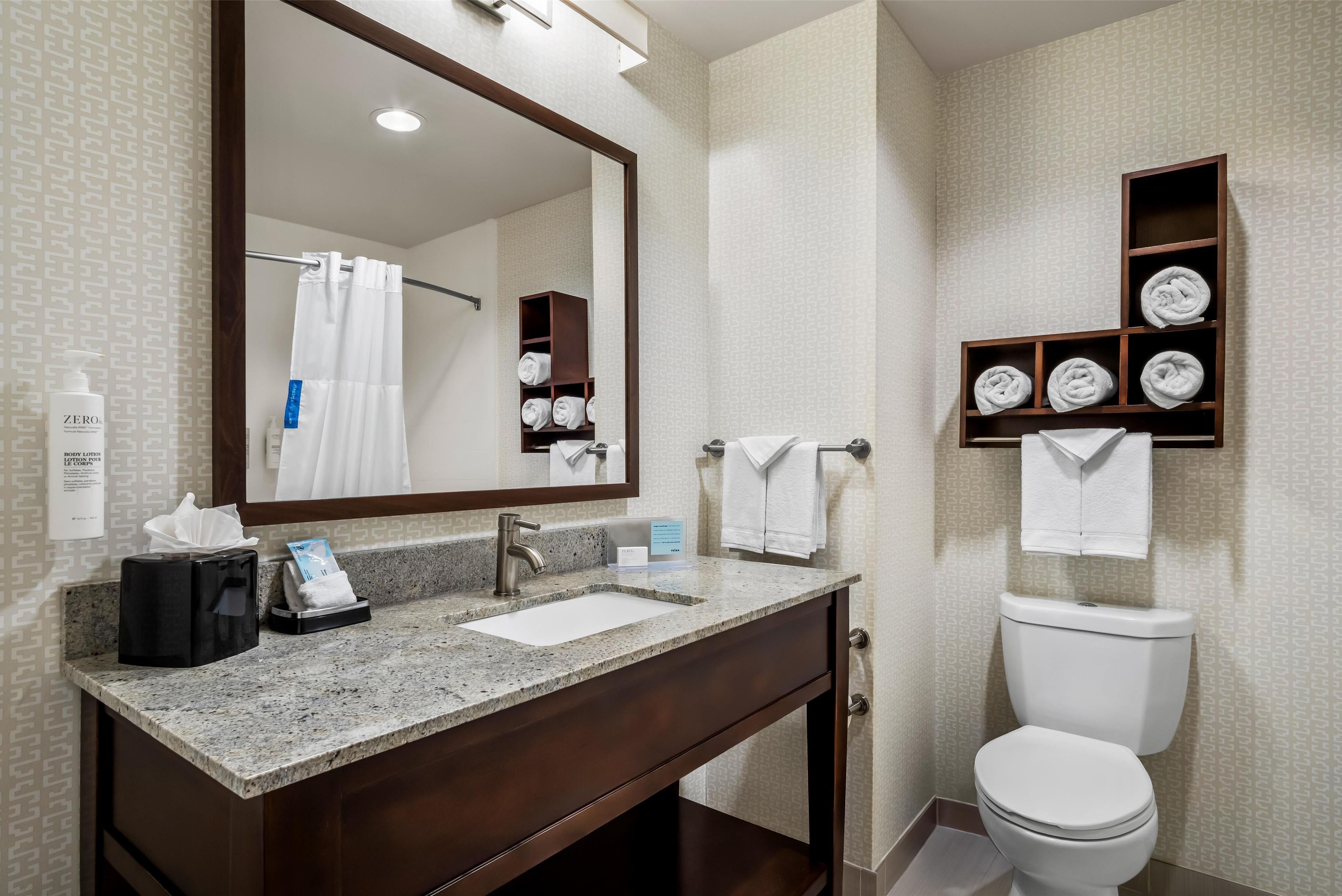 A bathroom with a sink, mirror, towel rack, and toilet.