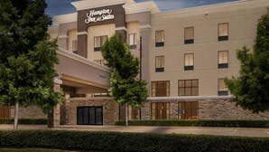 Ett Hampton Inn & Suites-hotell med en fasad av sten, många fönster och en framträdande entré.