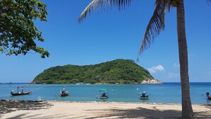 A beach with boats, a sandy shore, and a forested island in the background. - Maehaad Bay Resort (Ko Pha-ngan)