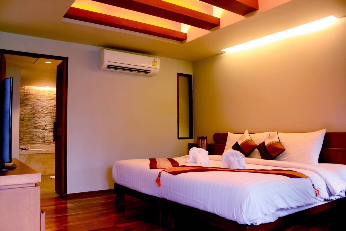 Une chambre d’hôtel équipée d’un lit, d’un téléviseur à écran plat, d’un système de climatisation et d’un mur en pierre.