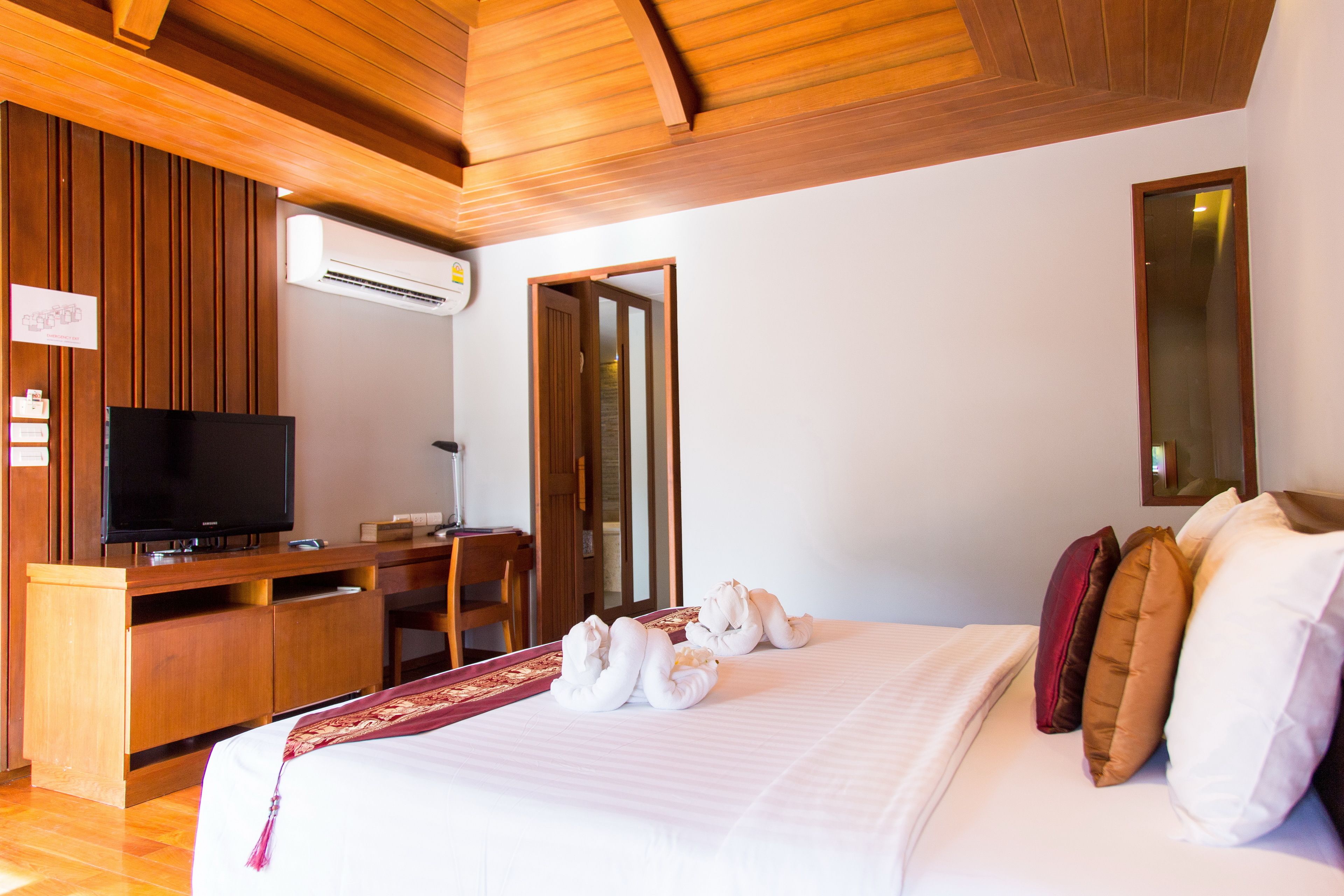 A hotel room with a bed, a desk, a television, and a mirror.