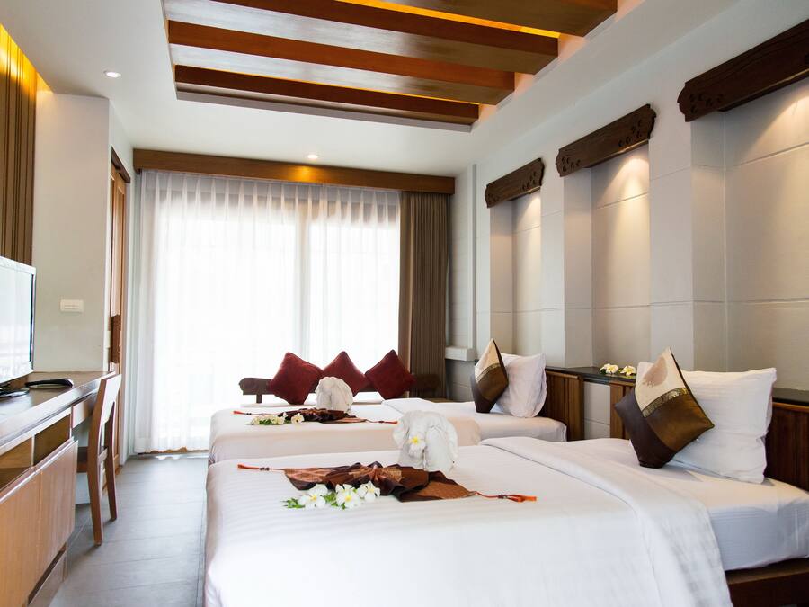 A hotel room with two beds, a desk, and a television.
