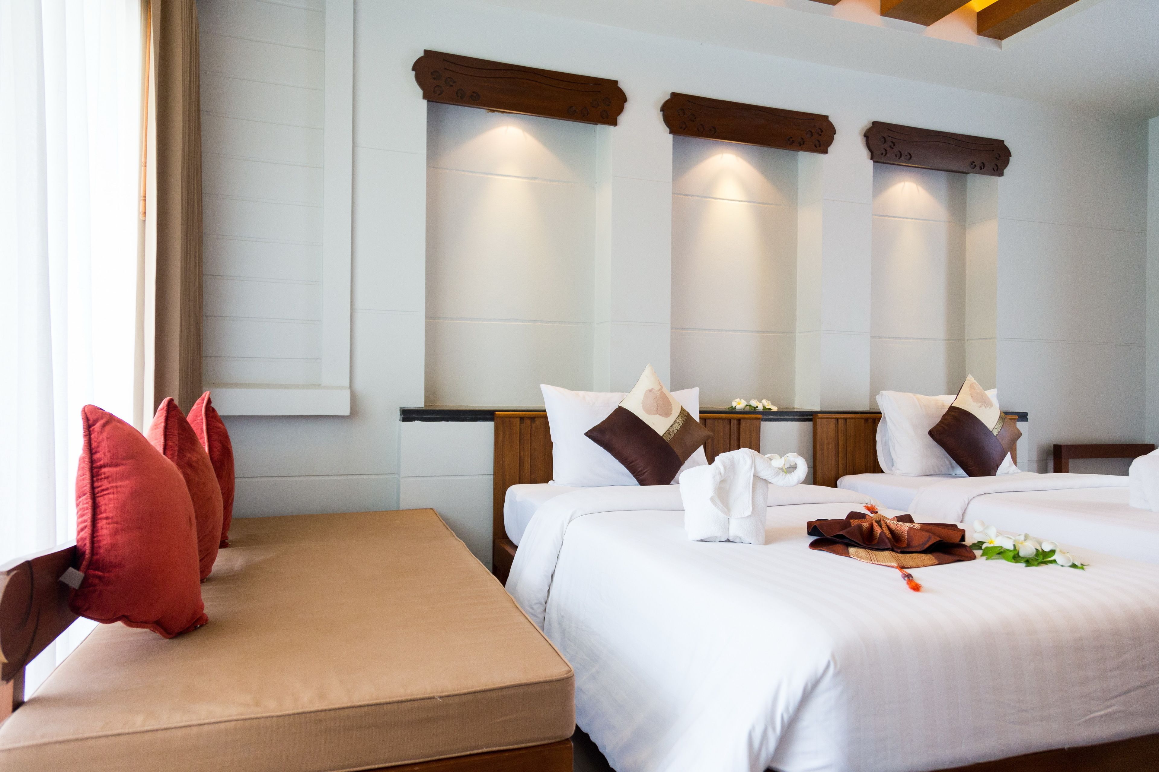 Ein Hotelzimmer mit zwei Betten, einer Bank und einem Fenster mit Jalousien.