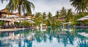 Una piscina al aire libre, sombrillas, tumbonas