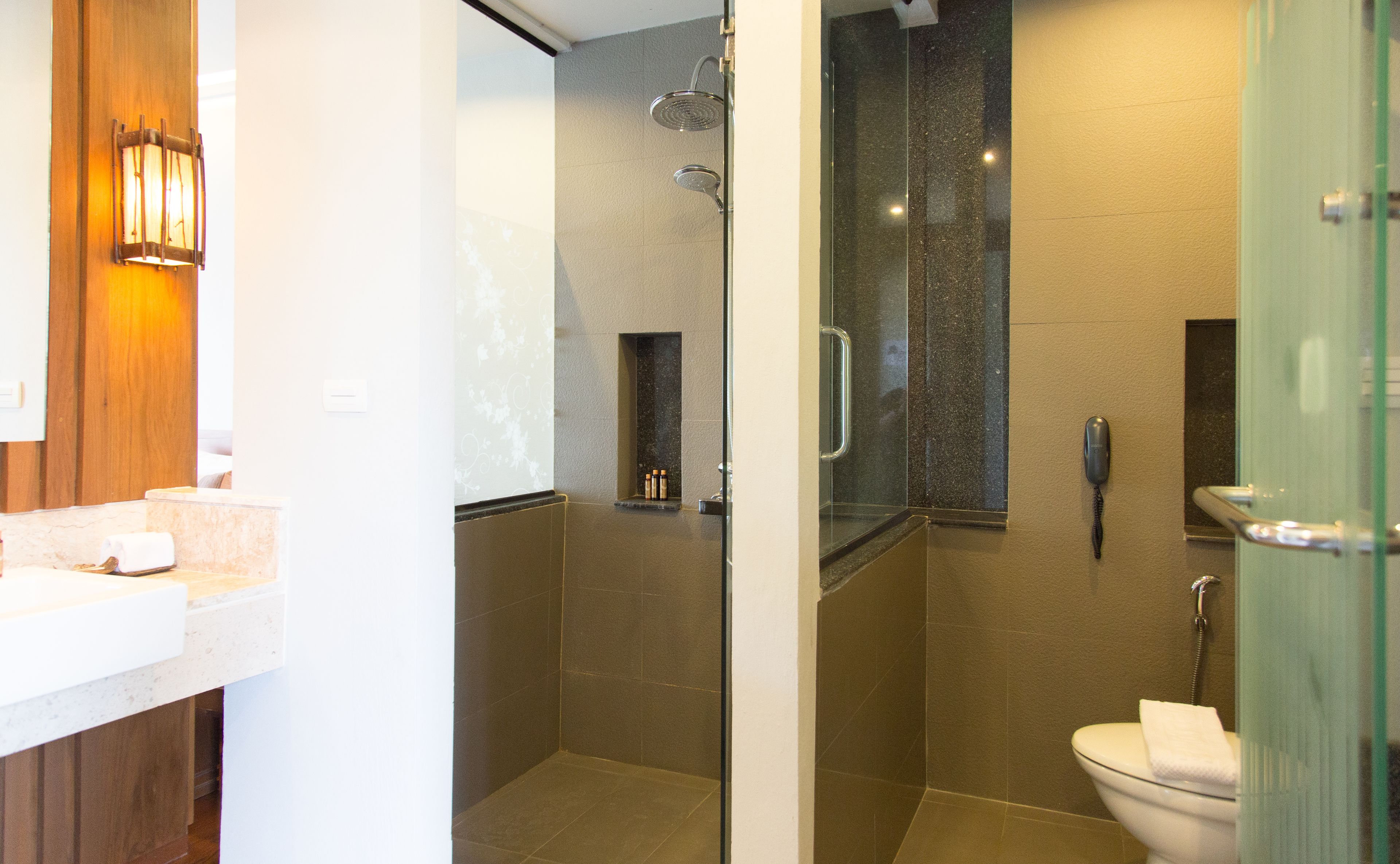 A modern bathroom with a glass shower enclosure, a toilet, and a vanity with a towel rack.