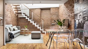 Ein modernes Wohnzimmer mit Treppe, einem Glastisch und einer Couch.