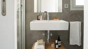 Une salle de bain moderne avec une porte de douche en verre, un lavabo blanc, un meuble-lavabo en bois et un porte-serviettes.