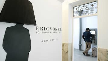 Hotelinterieur met een wandlamp, een man bij een zelfbedieningskiosk en een bordje voor Eric Vokel Boutique Apartments in Madrid Suites.