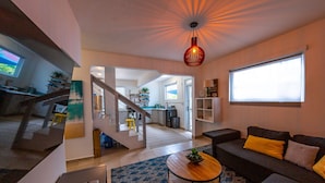 A modern living room with a sofa, coffee table, and a staircase leading to a kitchen. - Casa Verde Hotel - Steps to the Beach | Pool, Restaurant & Bar (Rincon)