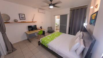 A hotel room with a bed, desk, chair, and a ceiling fan.