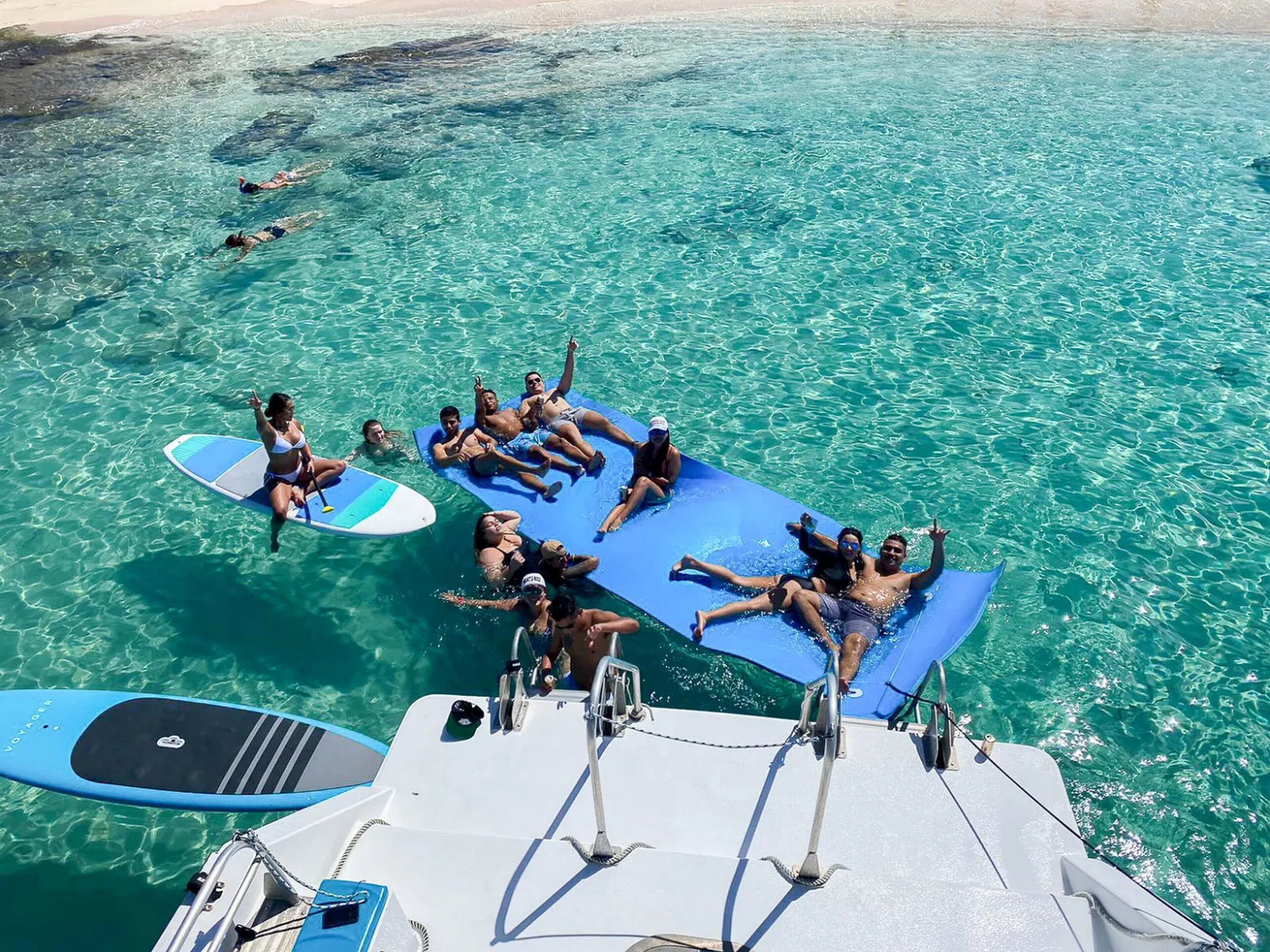 A group of people on a boat floating on clear turquoise water.