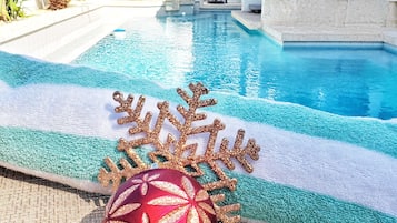 Una piscina al aire libre, sombrillas, sillones reclinables de piscina