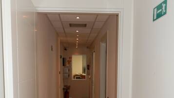 A narrow hallway with wooden flooring, white walls, and a door with a silver handle.