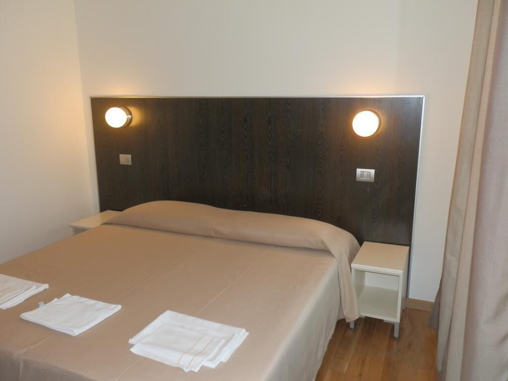 A neatly made bed with a headboard, two bedside tables, and a wall-mounted light fixture.