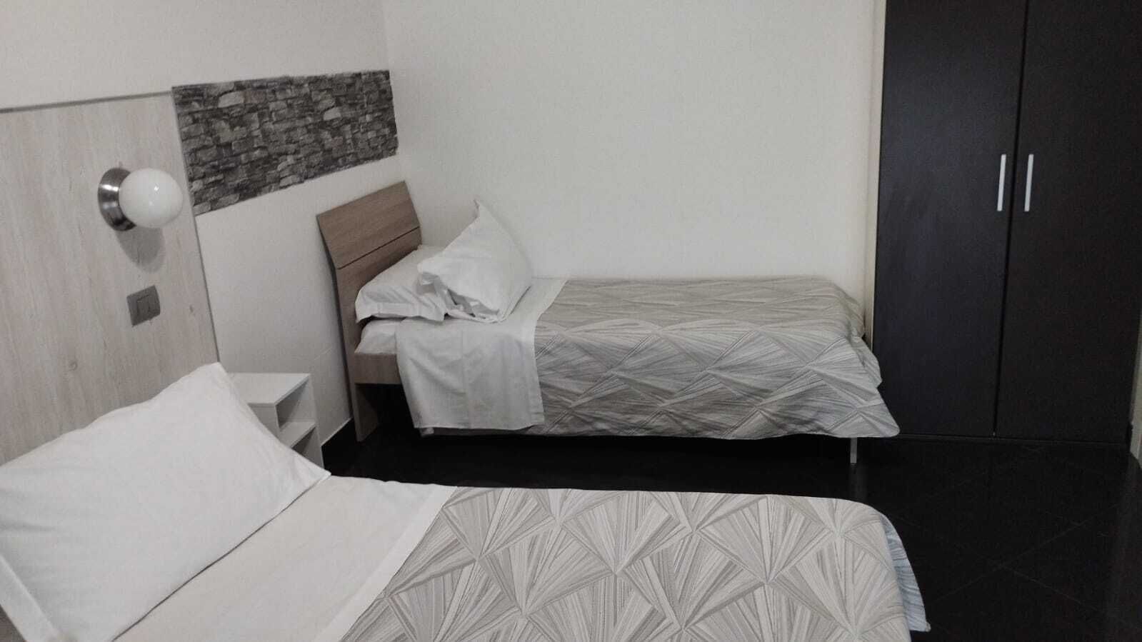 Ein Hotelzimmer mit zwei Betten, einem Kleiderschrank und einem kleinen Nachttisch.