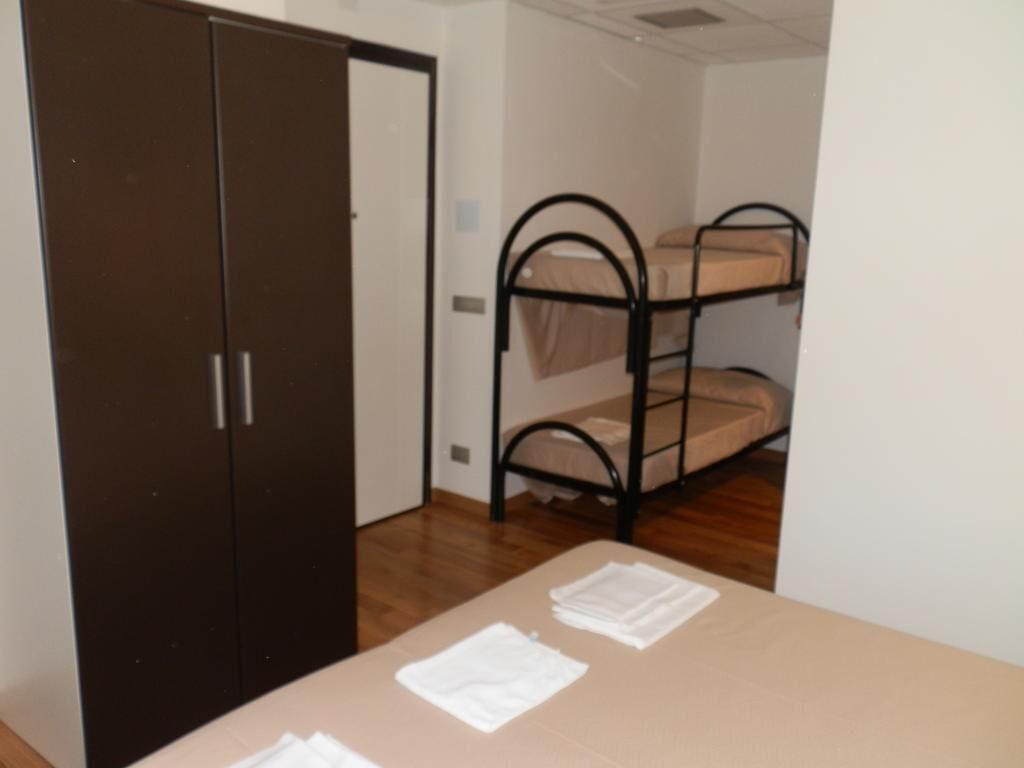 A room with a bunk bed, a wardrobe, and a table with folded clothes.