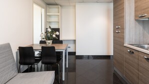 A modern kitchen with a dining area, featuring a wooden cabinet, a sink, and a dining table with chairs.