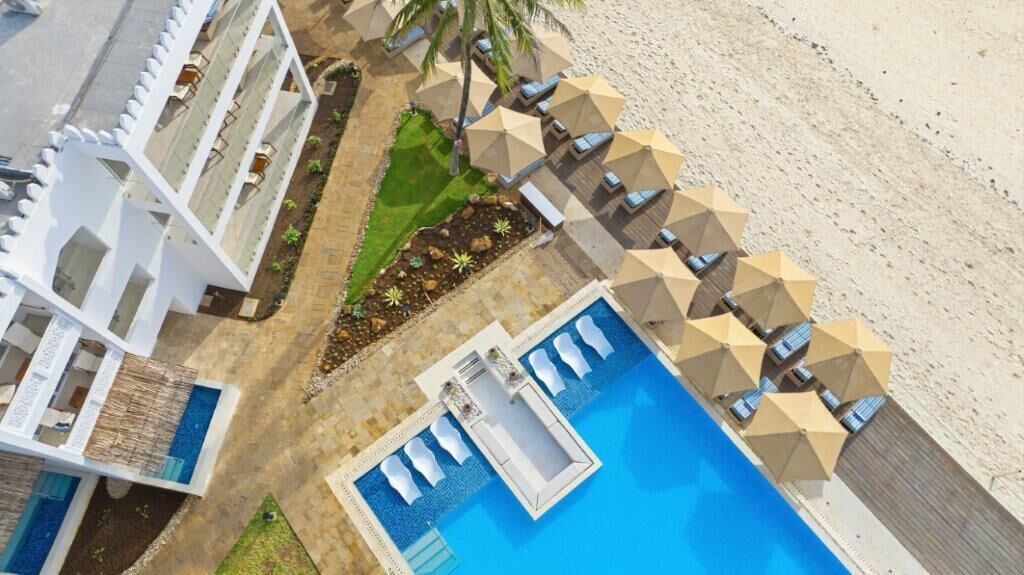 A resort with a pool, sun loungers, and a beach.