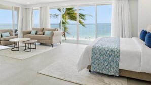 A hotel room with a large bed, two sofas, a small table, and a view of the ocean. - Bamburi Beach Hotel - All Inclusive (Mombasa)