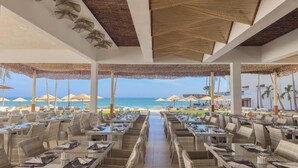 A beachside restaurant with wicker furniture, umbrellas, and a view of the ocean. - Bamburi Beach Hotel - All Inclusive (Mombasa)