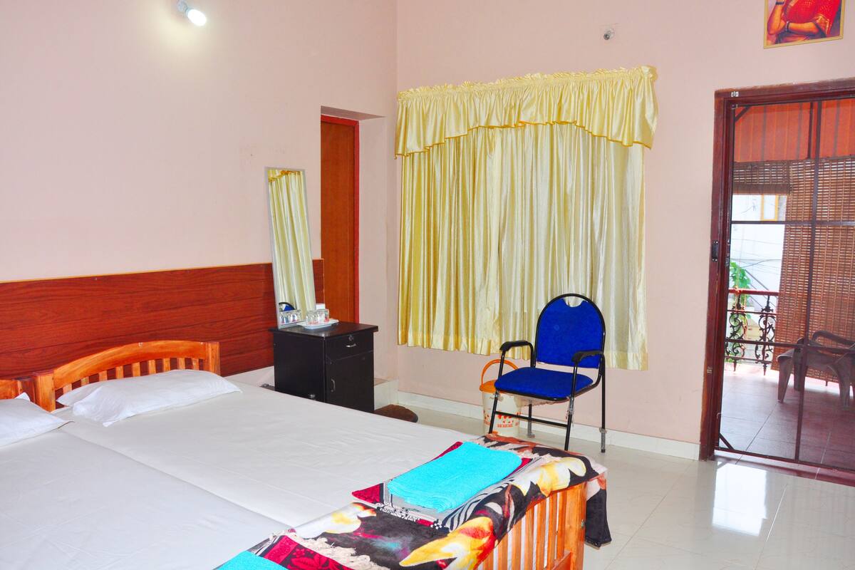 A bedroom with a bed, a chair, a nightstand, and a window with curtains.