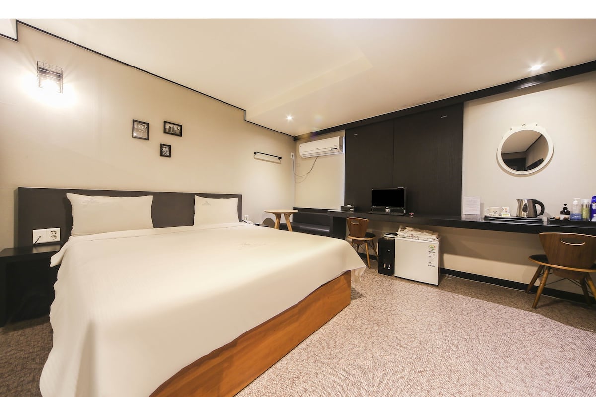 Ein Hotelzimmer mit Bett, Schreibtisch, Stuhl und einer kleinen Küchenzeile.