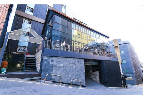 A modern building with a glass facade, a visible entrance, and a staircase leading to an upper level.