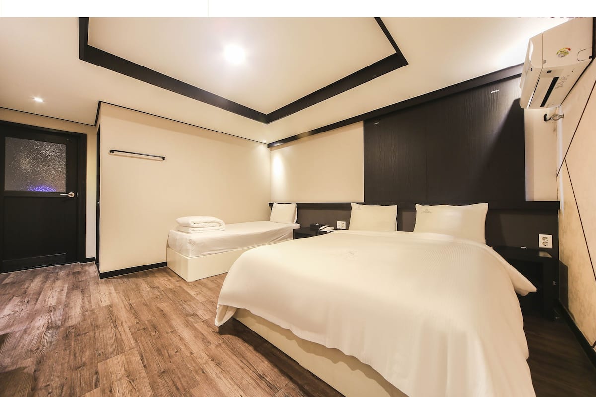 Ein modernes Hotelzimmer mit einem großen Bett, Nachttischen, einer kleinen Sitzecke und einer Deckenleuchte.