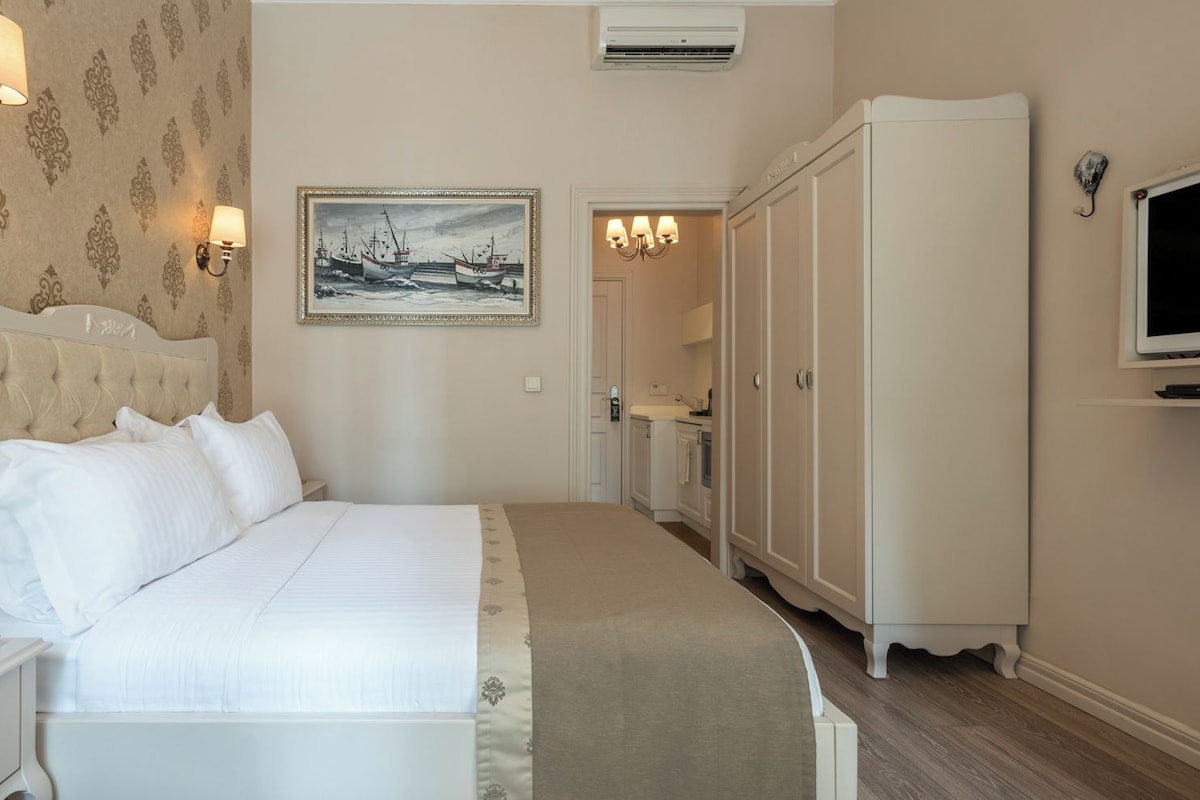 A hotel room with a bed, a wardrobe, a painting, and a television.