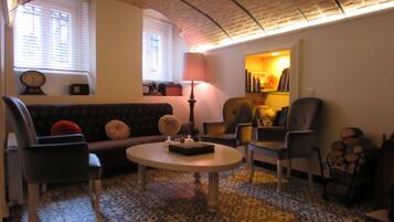 A living room with a round coffee table, two armchairs, a sofa, and a lamp.