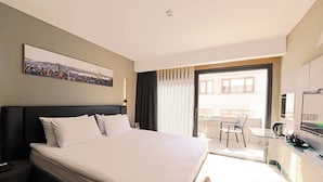 Une chambre d’hôtel avec un grand lit, un bureau avec une chaise, une télévision et un balcon avec vue.