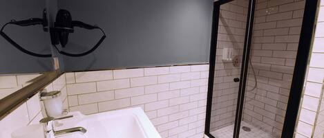 A bathroom with a white sink, a mirror, and a shower area with a glass door.