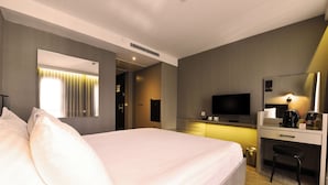 Une chambre d’hôtel avec un grand lit, un bureau avec une chaise, une télévision et un miroir.