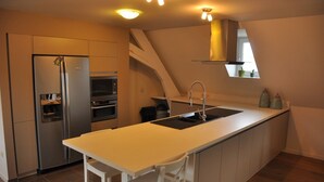 Una cocina moderna con una isla central, horno empotrado y refrigerador de acero inoxidable.