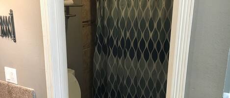 A small bathroom with a toilet, a shower curtain, and a towel rack.