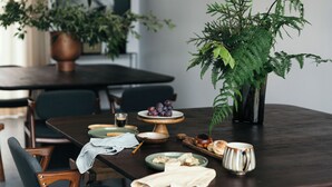 Una mesa de comedor con platos, un pastelero y un helecho en maceta.