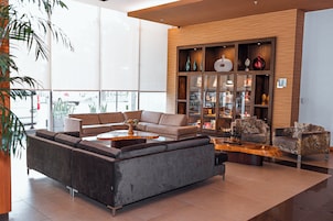 Una sala moderna con un sofá seccional, una mesa de centro y un mueble de madera con objetos decorativos.