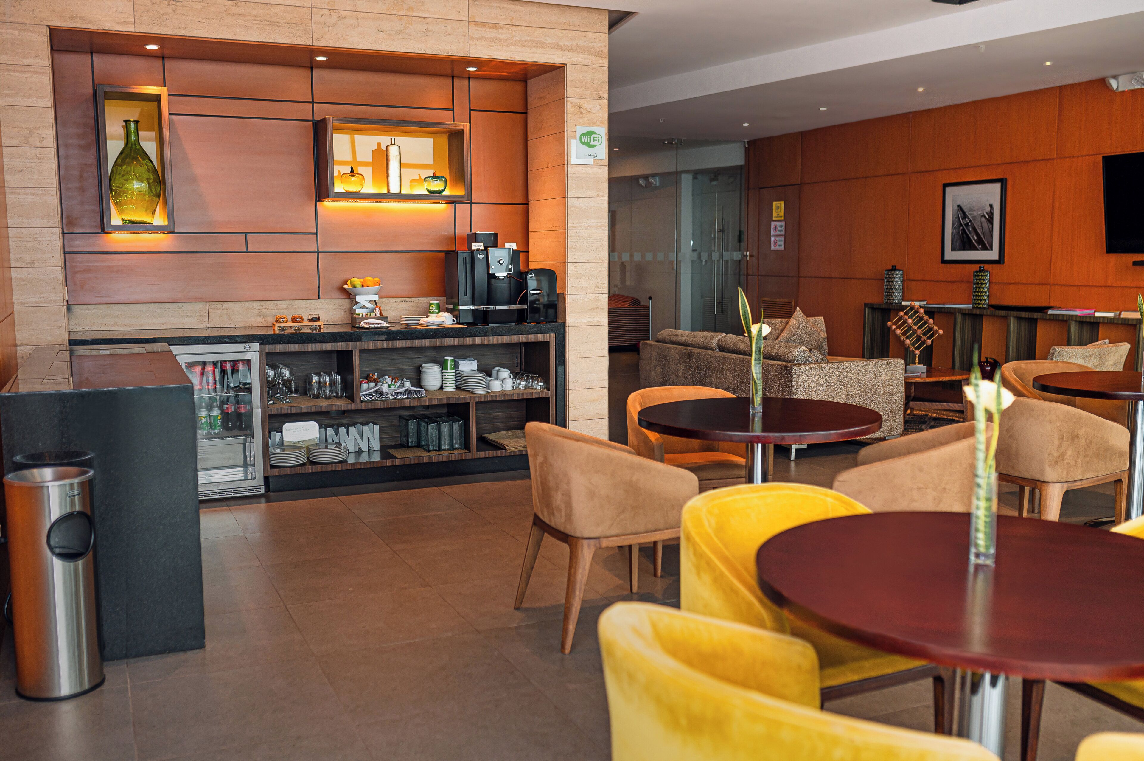 Un área de bar moderna con asientos y una cafetera.