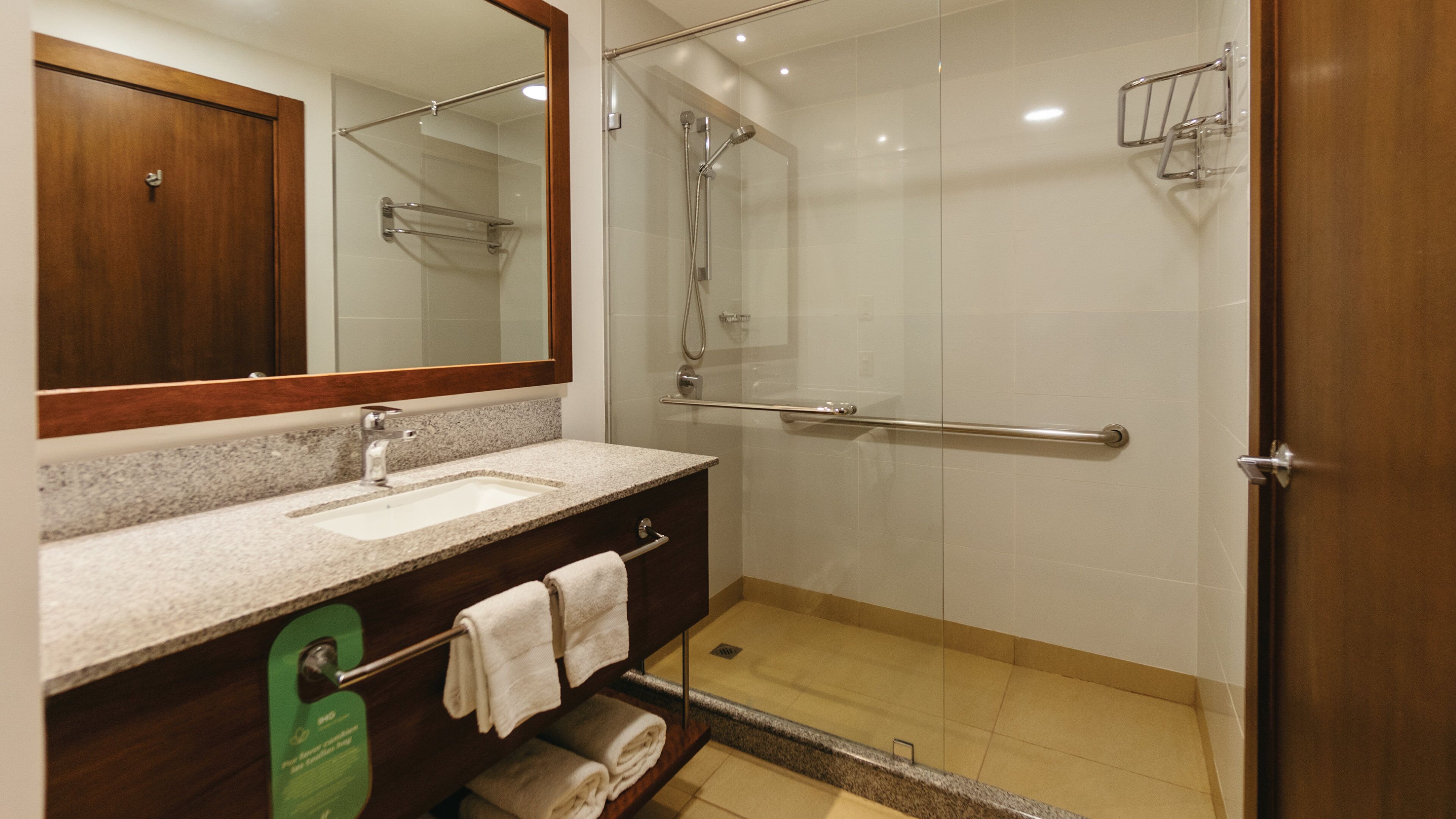 A bathroom with a glass-enclosed shower, a sink with a towel rack, and a wooden cabinet.