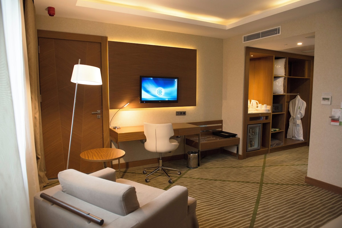 Une chambre d’hôtel équipée d’une télévision, d’un bureau, d’une chaise, d’un peignoir et d’une armoire.