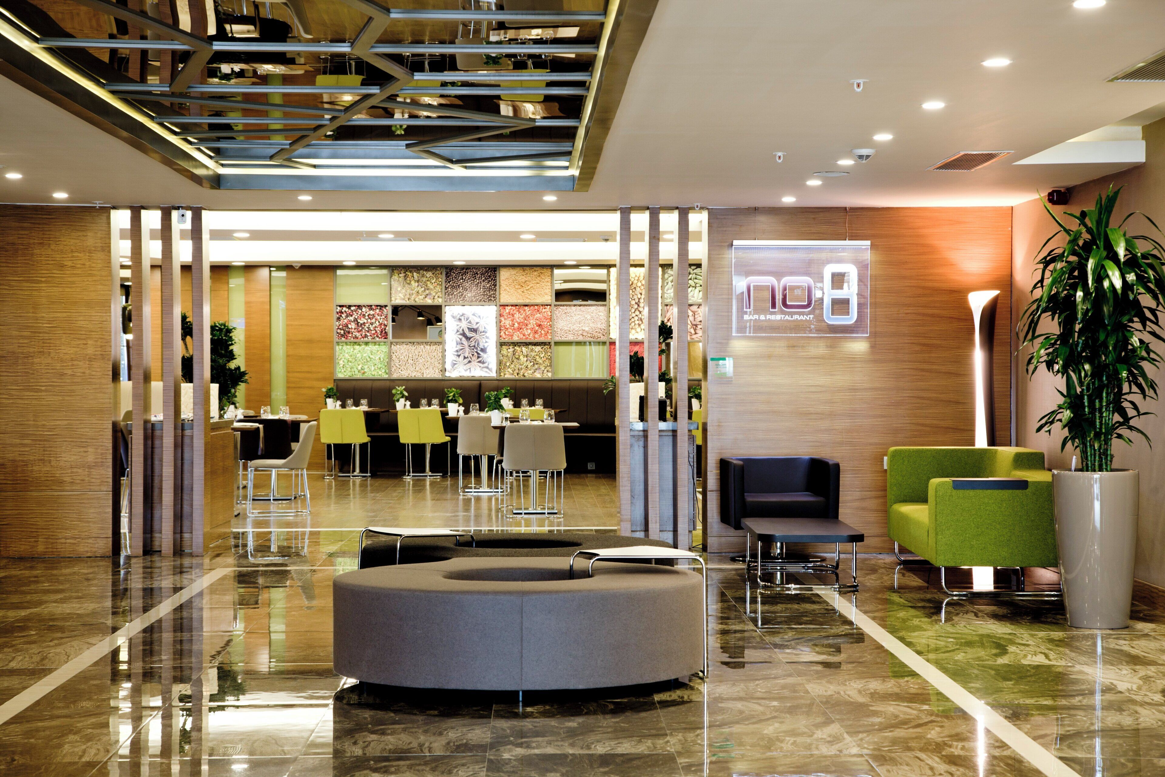 A modern lobby with a reception desk, seating area, and a bar.