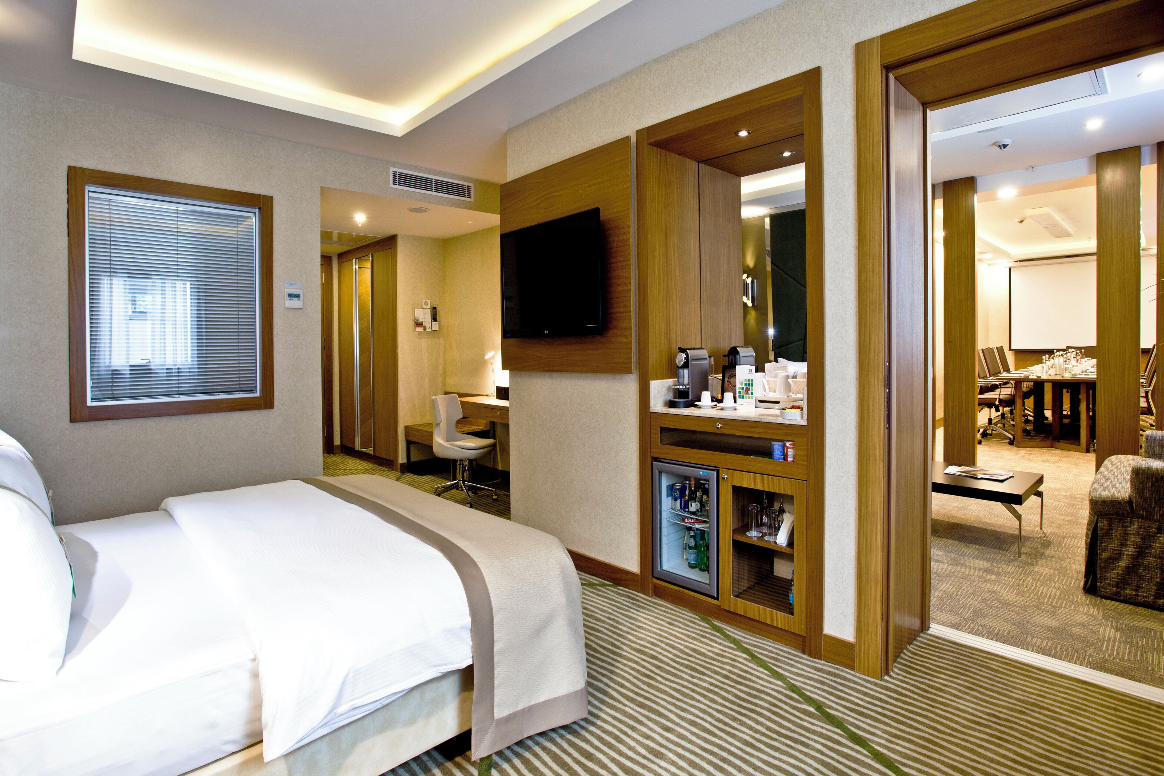 Ein Hotelzimmer mit einem Bett, einem Schreibtisch, einem Fernseher und einer Minibar.