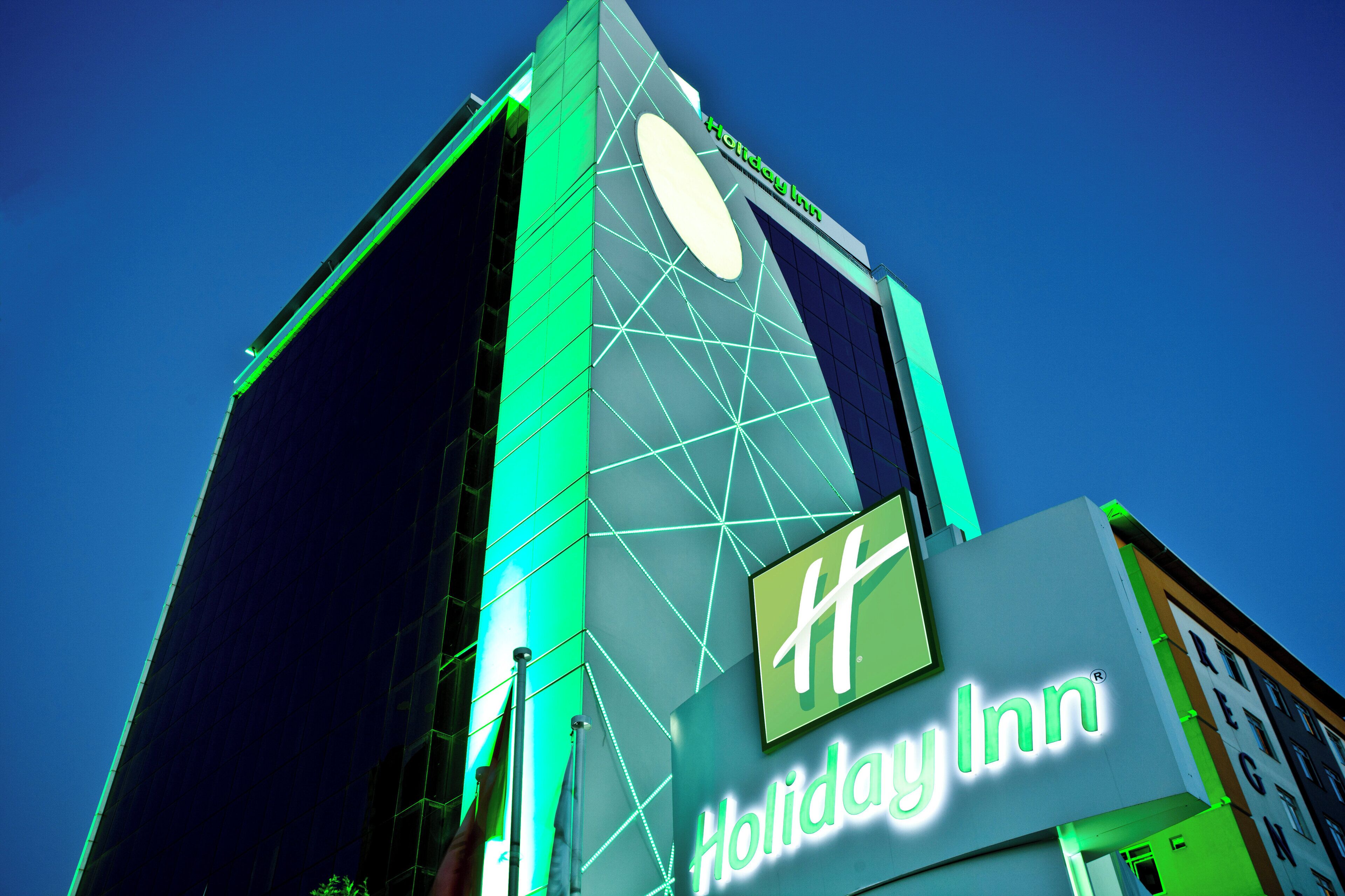 Ein hohes Gebäude mit einem gut sichtbaren 'Holiday Inn'-Schild am Fuße.